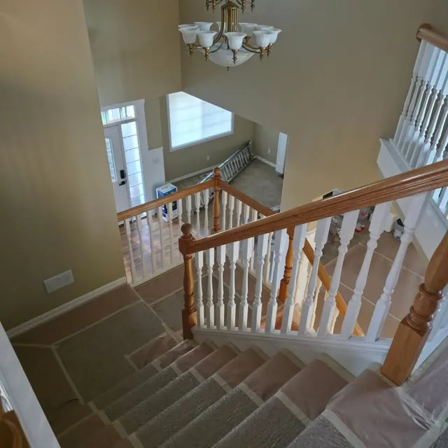 Two-story staircase interior prepped and masked for repaint